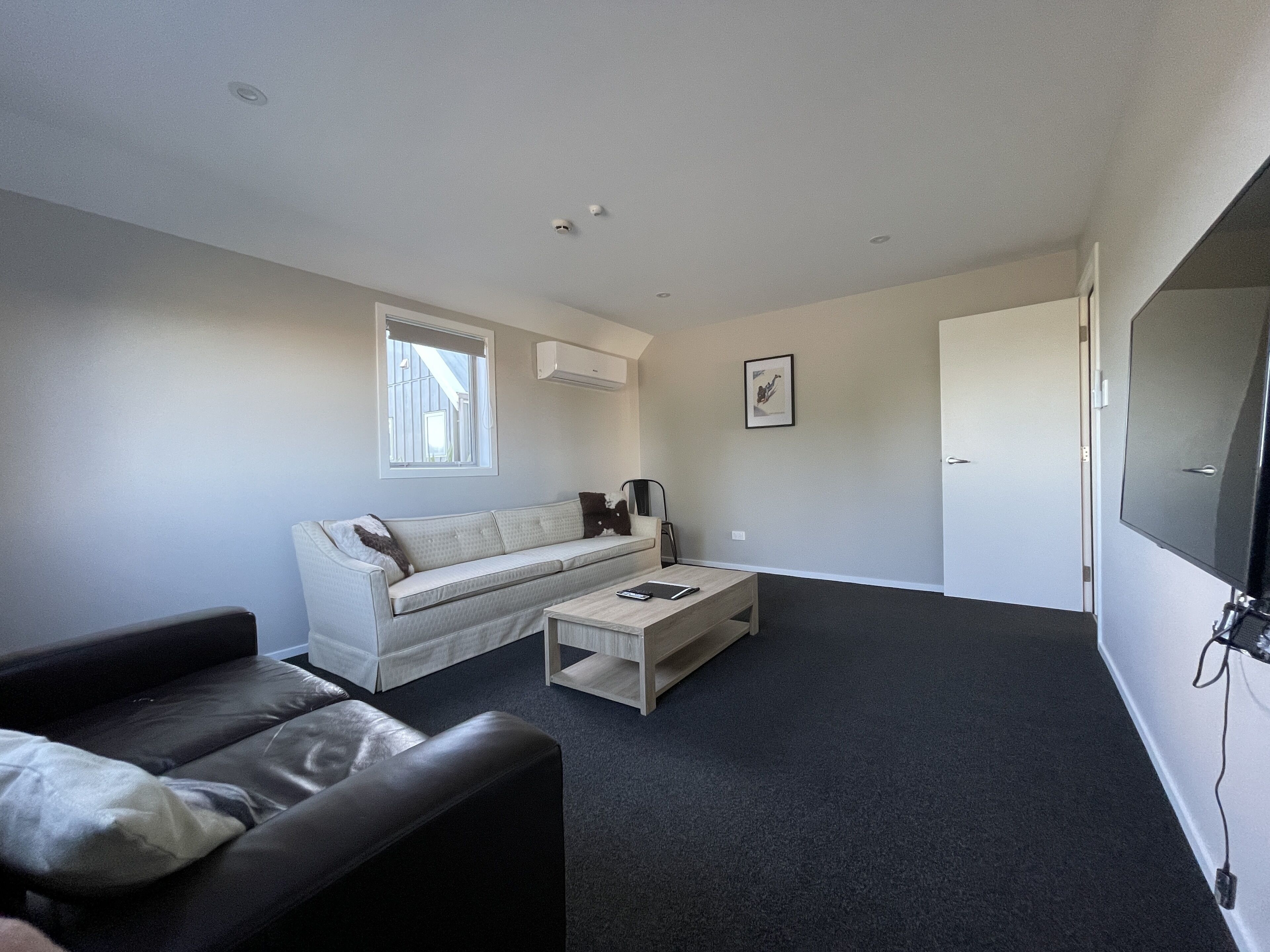 A modern living room with a sofa, a coffee table, and a TV.