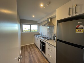 A modern kitchen with a stainless steel refrigerator, a gas stove, and a window providing a view of the outdoors. - Pudding Hill Lodge & Chalets (Methven)