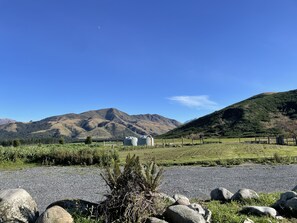 A rural landscape with mountains, a gravel path, and several large storage tanks. - Pudding Hill Lodge & Chalets (Methven)