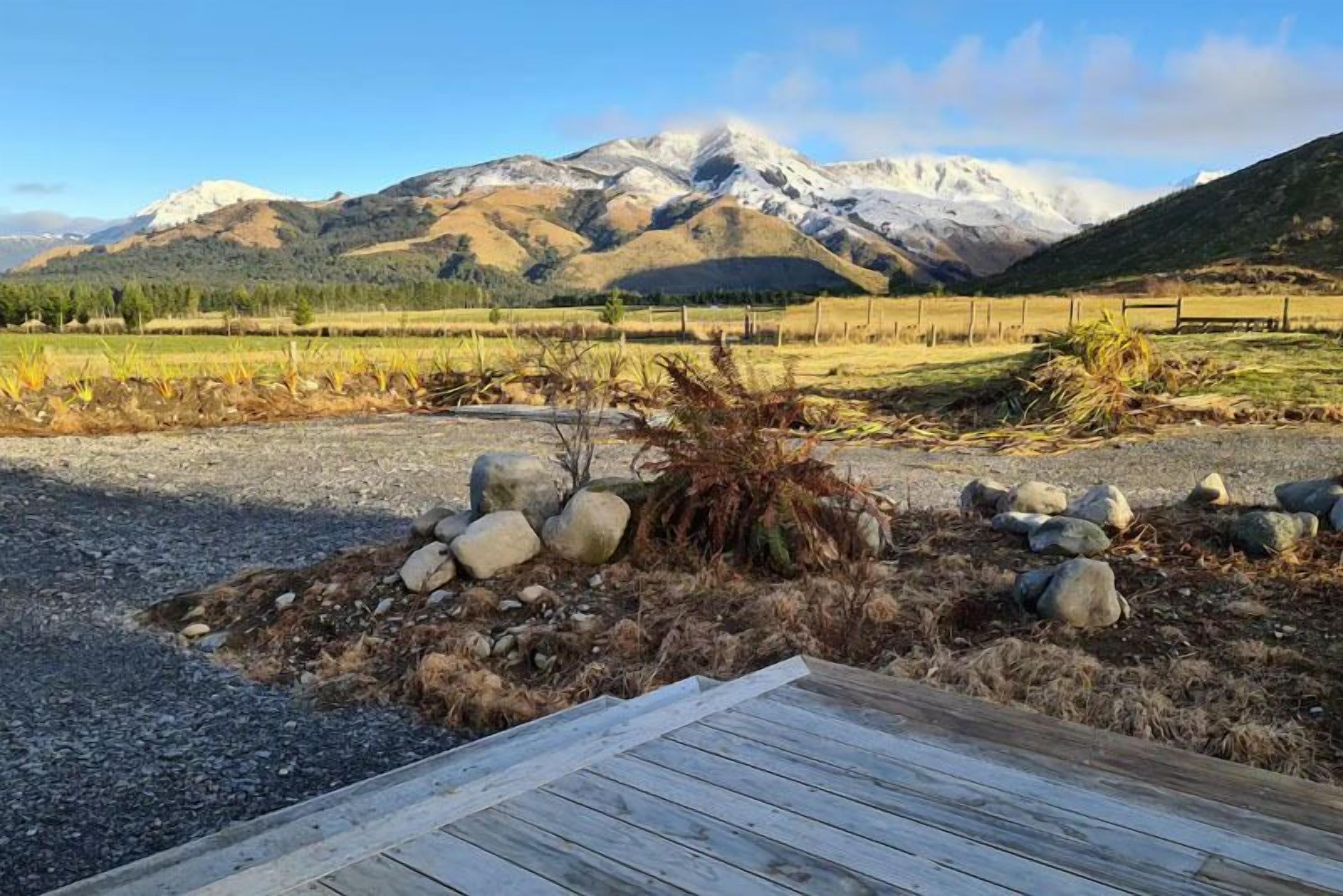 Une terrasse en bois qui mène à un paysage montagneux sous un ciel dégagé.