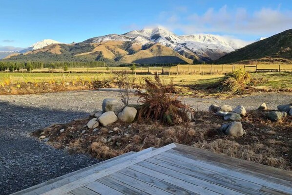 A wooden deck leading to a mountainous landscape with a clear sky. - Pudding Hill Lodge & Chalets (Methven)