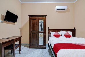A bedroom with a bed, a desk, a wardrobe, and a mounted TV. - Hotel O Sandira Syariah (Dumai)