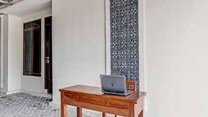 A wooden table with a laptop, a patterned wall, and a tiled floor. - Hotel O Sandira Syariah (Dumai)