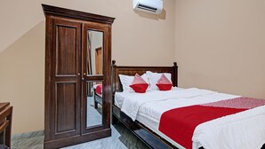 A bedroom with a wooden wardrobe, a bed with white bedding and red accents, and an air conditioning unit on the wall. - Hotel O Sandira Syariah (Dumai)