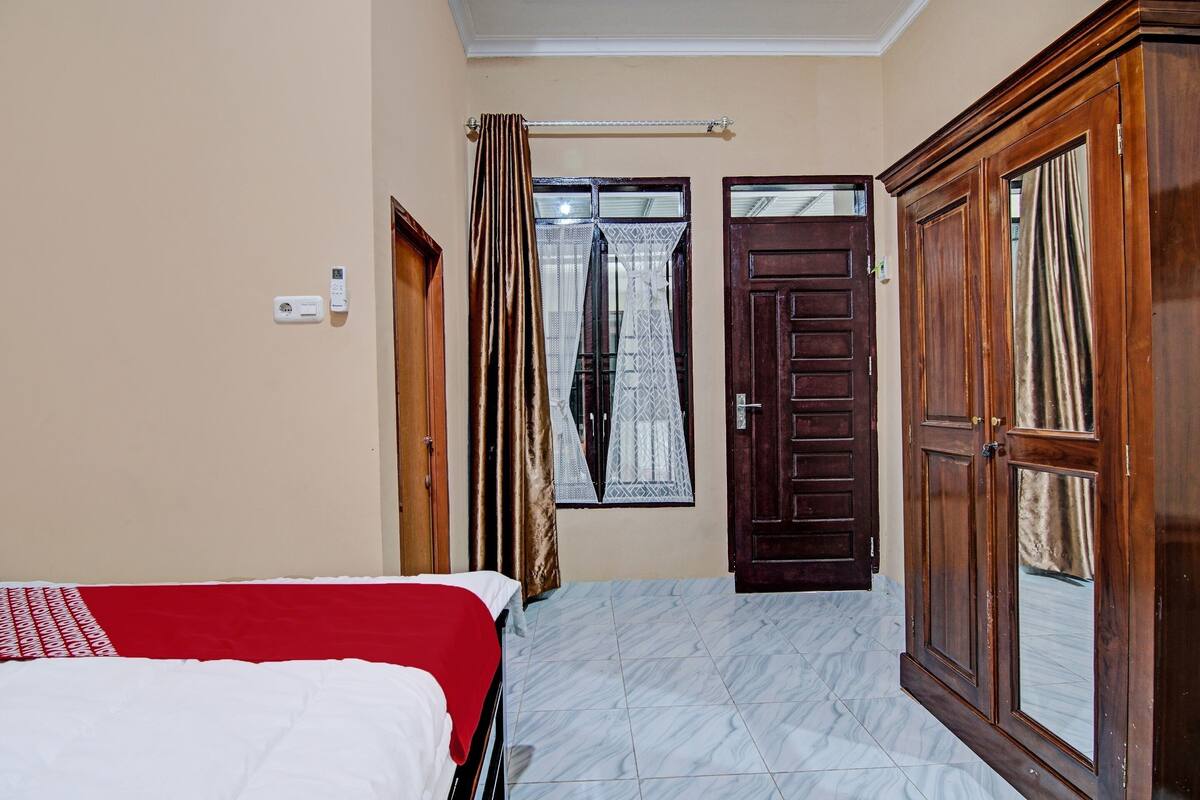A bedroom with a bed, a wardrobe, a door, and a window with curtains.