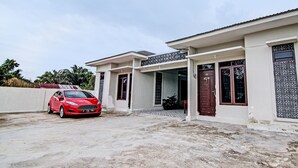 A modern two-story house with a covered driveway, a parked red car, and a motorcycle. - Hotel O Sandira Syariah (Dumai)