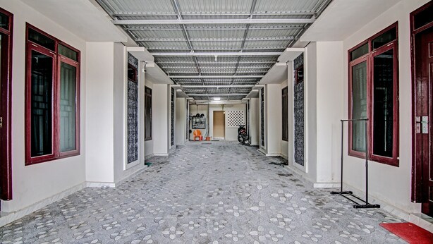 A hallway with patterned flooring, metal ceiling, and red-framed windows. - Hotel O Sandira Syariah (Dumai)