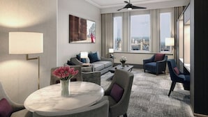 Ett modernt hotellrum med utsikt över staden, ett runt bord i marmor och bekväma sittplatser.