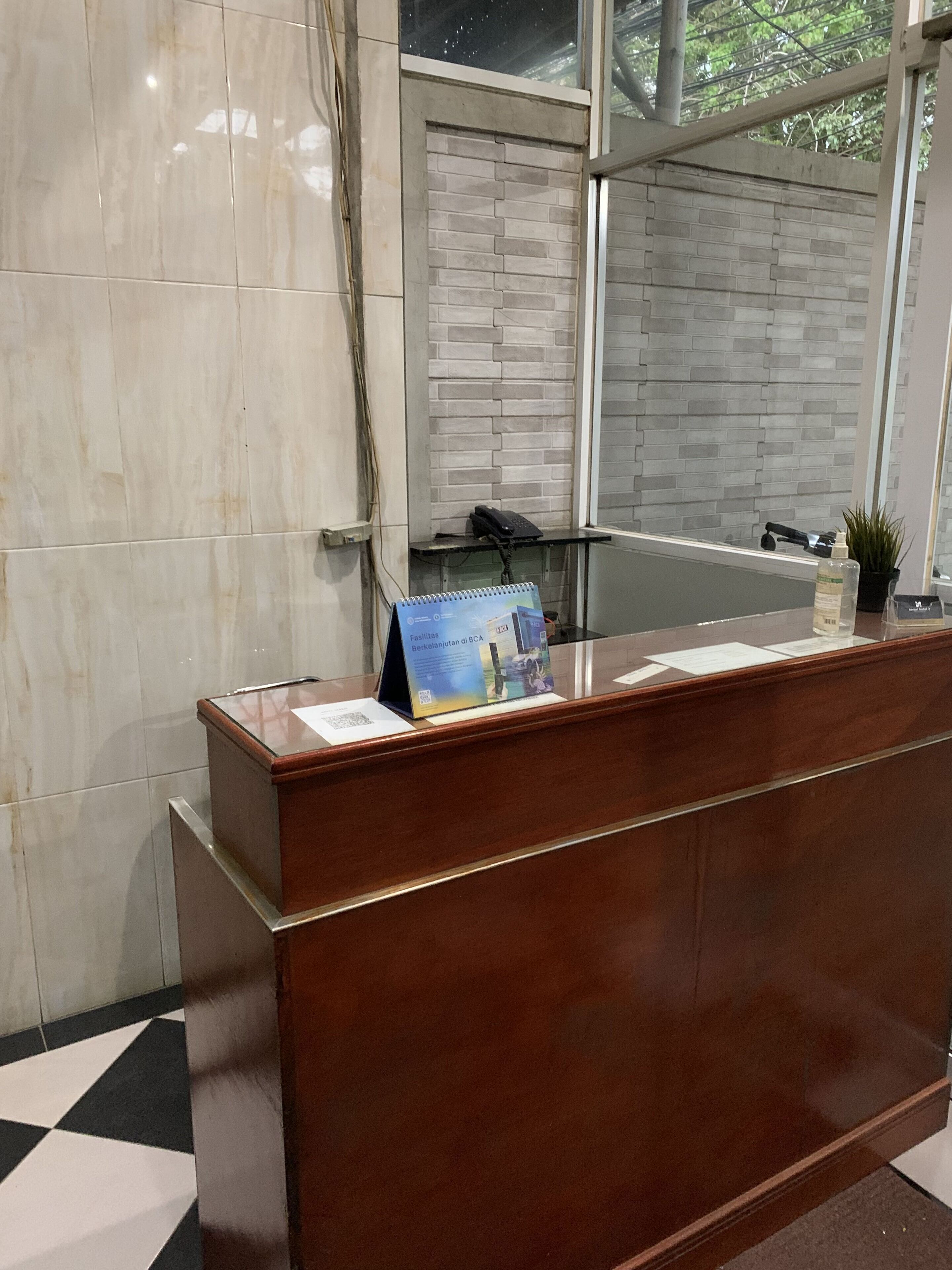 A reception desk with a brochure, a phone, and a small plant.