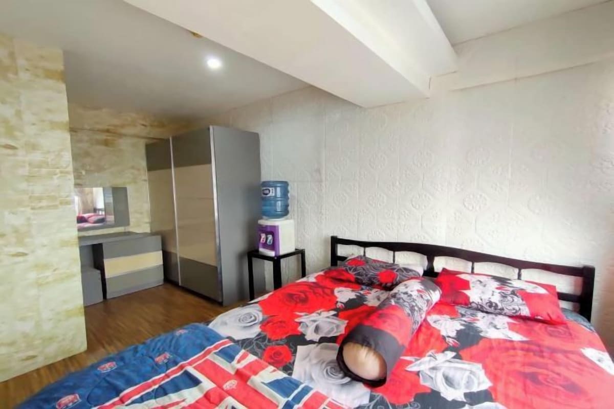A bedroom with a bed, a wardrobe, a water dispenser, and a desk.