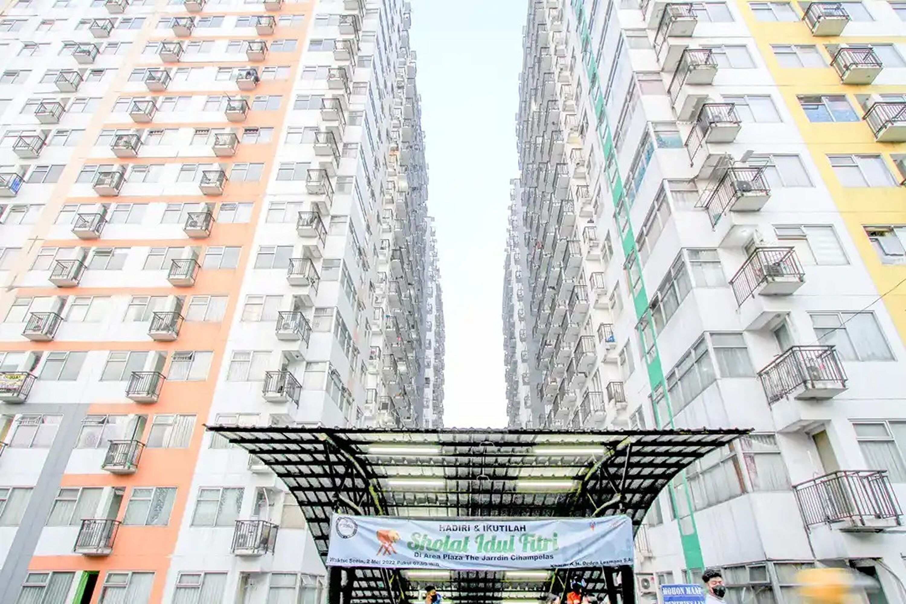 Un edificio residencial de gran altura con varios balcones y un cartel anunciando un evento.