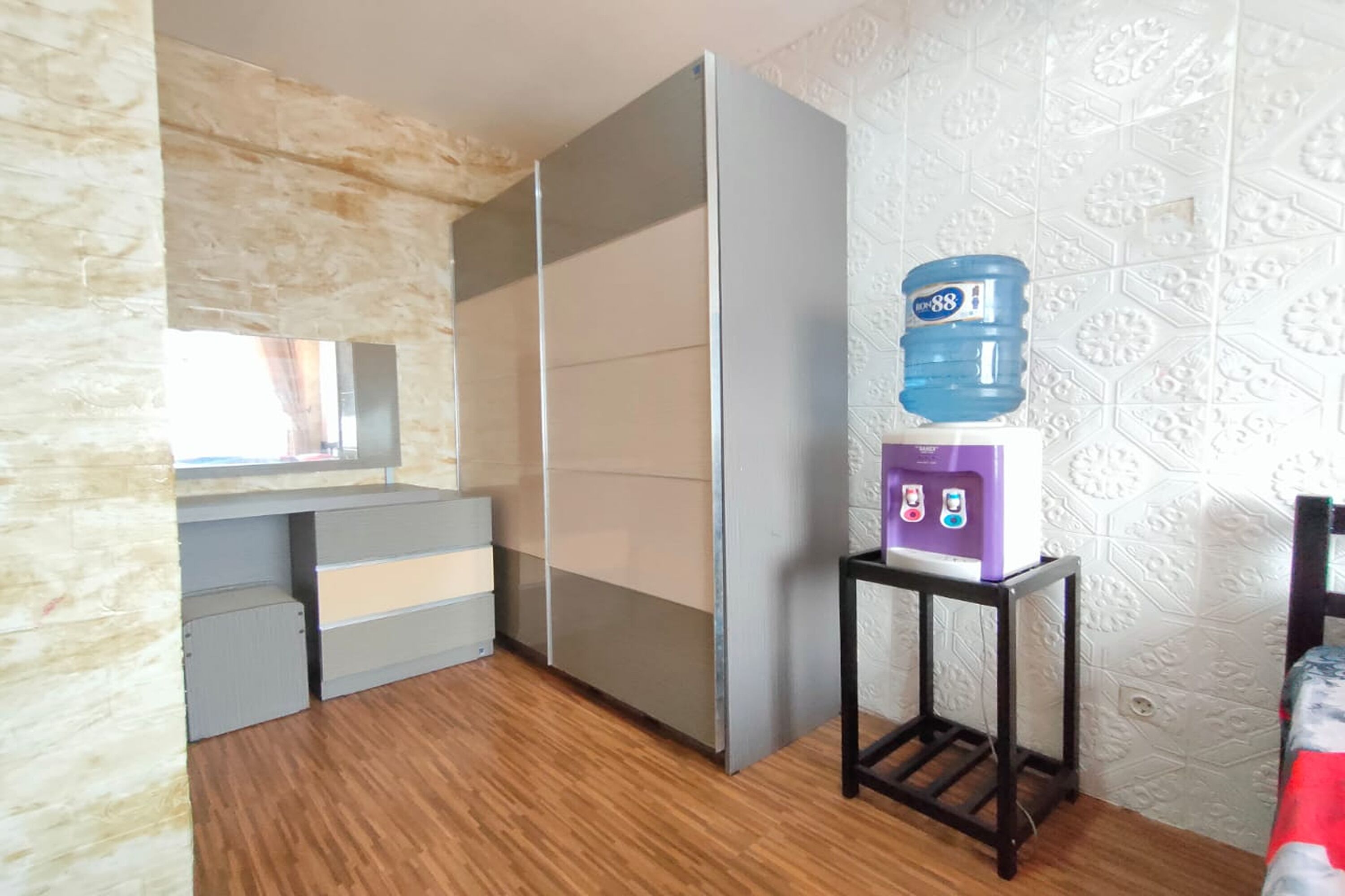 A room with a sliding door, a water dispenser, and a small table with a chair.