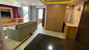 A modern living room with a sofa, a flat-screen TV, and a wooden cabinet. - Cozy Room @ Hallo Tidur By Tio (Bandung)