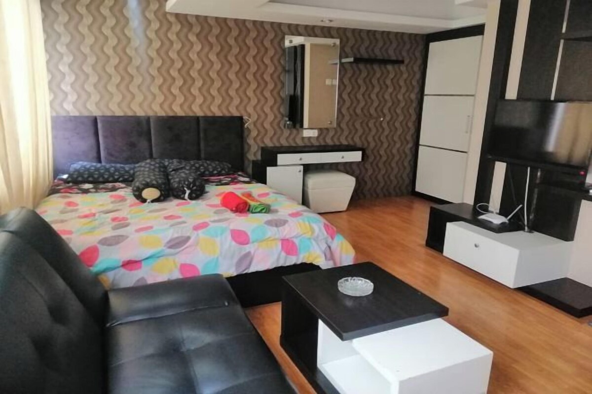 Une chambre moderne comprenant un lit, un canapé, une petite table, une armoire et un téléviseur.