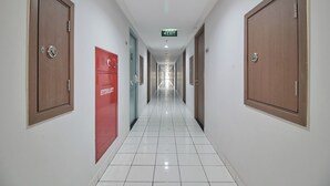 A hallway with wooden doors, a red cabinet labeled "HYDRANT," and an exit sign. - Room Rendi @ Podomoro Golf View (Gunung Putri)