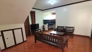 A living room with a sofa, two wooden tables, a TV, and a cabinet. - Rachel's Bed and Breakfast Near Tagaytay (Silang)