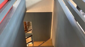 A modern staircase with metal railings and a dark wall. - Rachel's Bed and Breakfast Near Tagaytay (Silang)