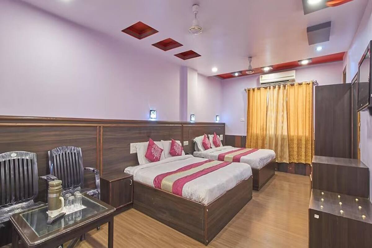 A hotel room with two beds, a desk, chairs, and a wardrobe.