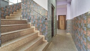 Una escalera con escalones de granito y paredes con mosaicos coloridos, que conduce a una puerta con diseño geométrico.