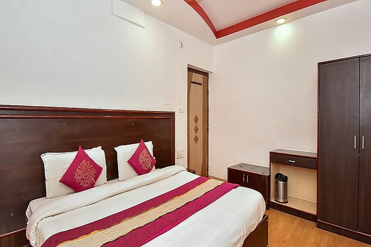 A neatly arranged hotel room with a large bed, a wardrobe, and a small bedside table.