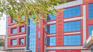Un hotel moderno con fachada roja y azul, ventanas grandes y una entrada visible.
