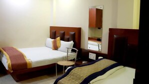A hotel room with two beds, a small round table, a mirror, and a wooden headboard. - Hotel Prem Deluxe Guest House (New Delhi)