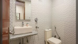 A bathroom with a white sink, mirror, and toilet. - Hotel Prem Deluxe Guest House (New Delhi)