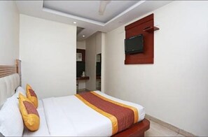 A hotel room with a bed, a television mounted on the wall, and a wooden headboard. - Hotel Prem Deluxe Guest House (New Delhi)