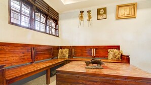A room with wooden benches, a central table with a fish sculpture, and wall-mounted decorations including framed pictures and a book. - Hotel O Nakula Sadewa (Depok)