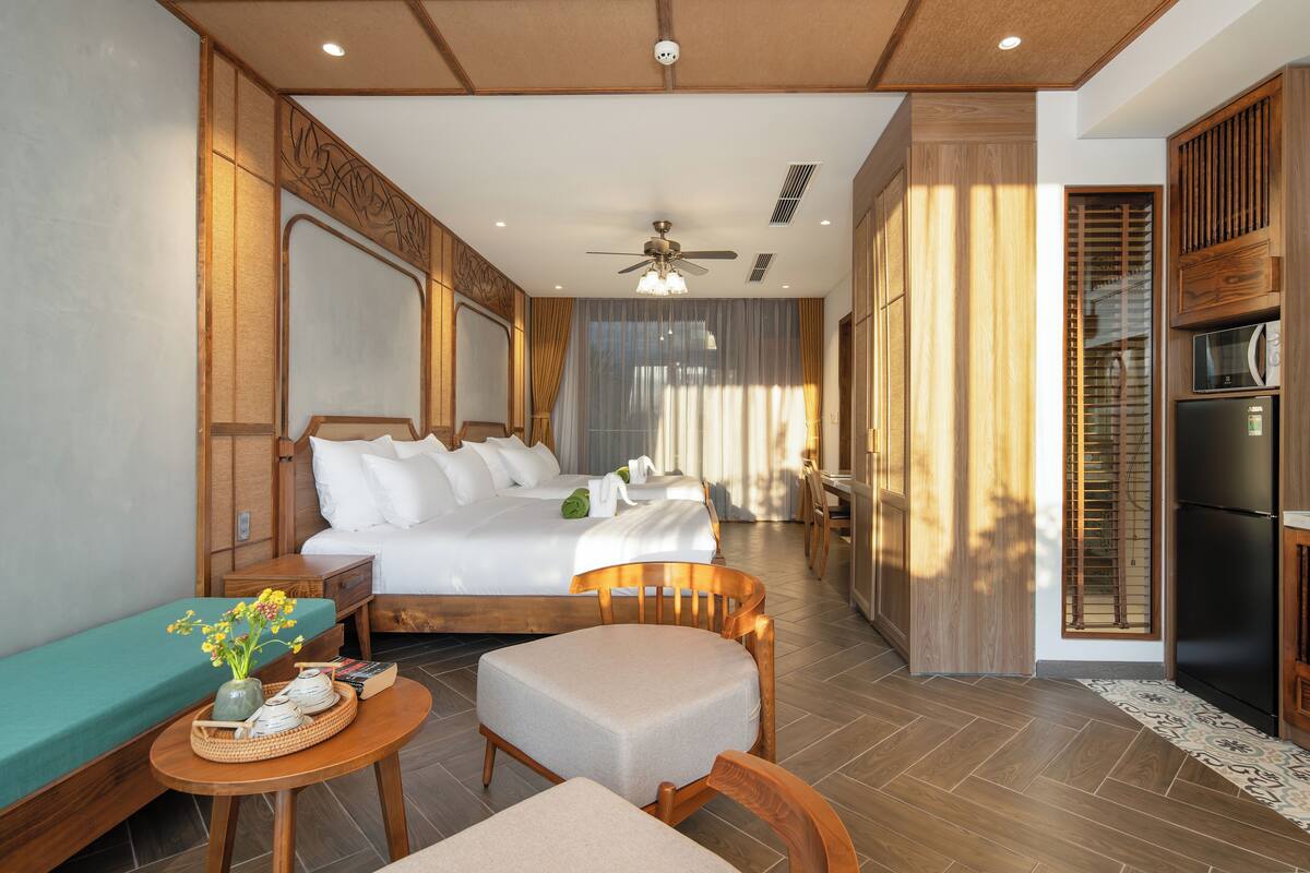 A hotel room with a bed, a seating area with a table, and a kitchenette.