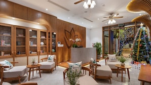 Um hall moderno com mobiliário de madeira, um pinheiro de Natal e uma mesa de recepção.