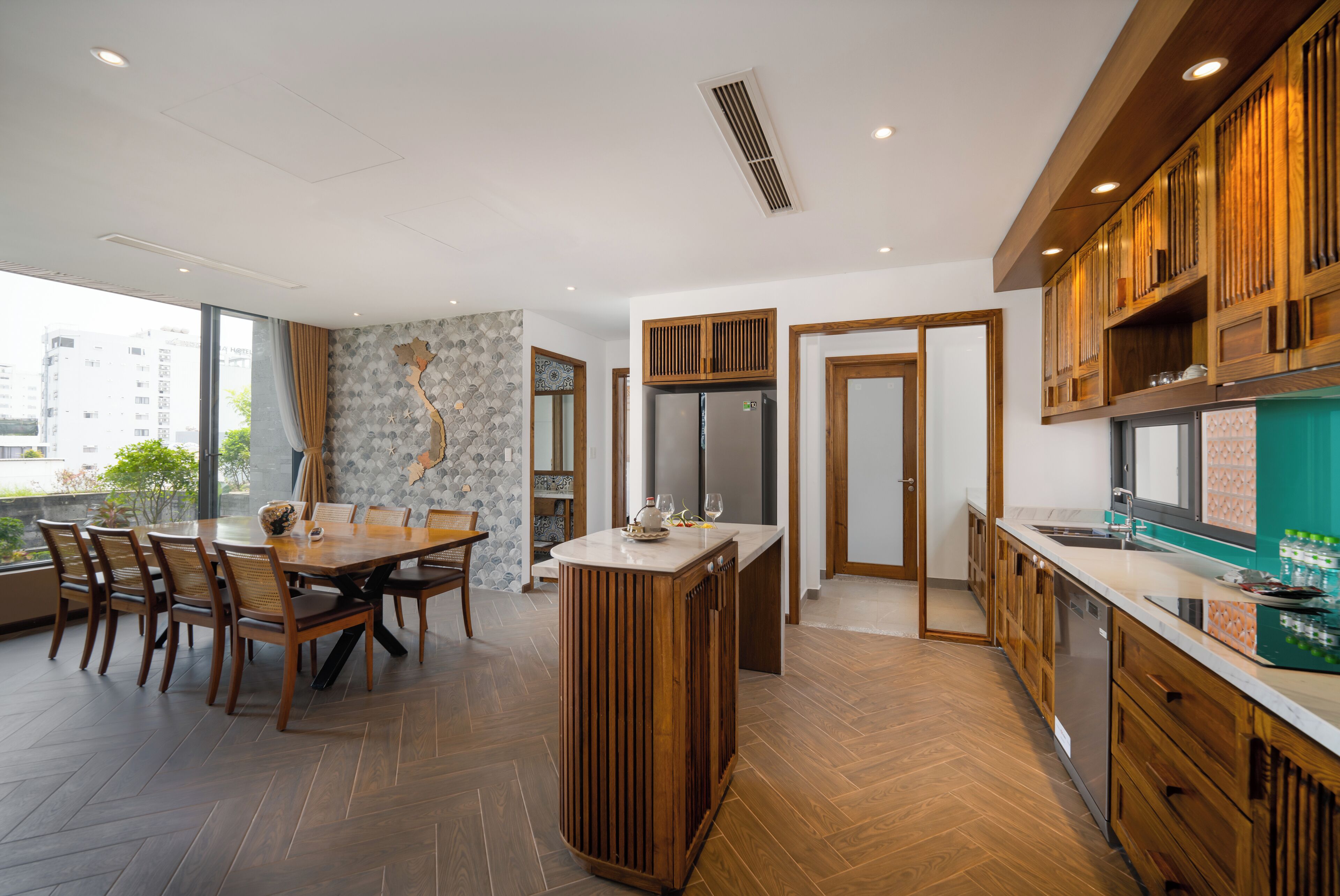 Una cocina moderna con armarios de madera, una isla central y un comedor con sillas.