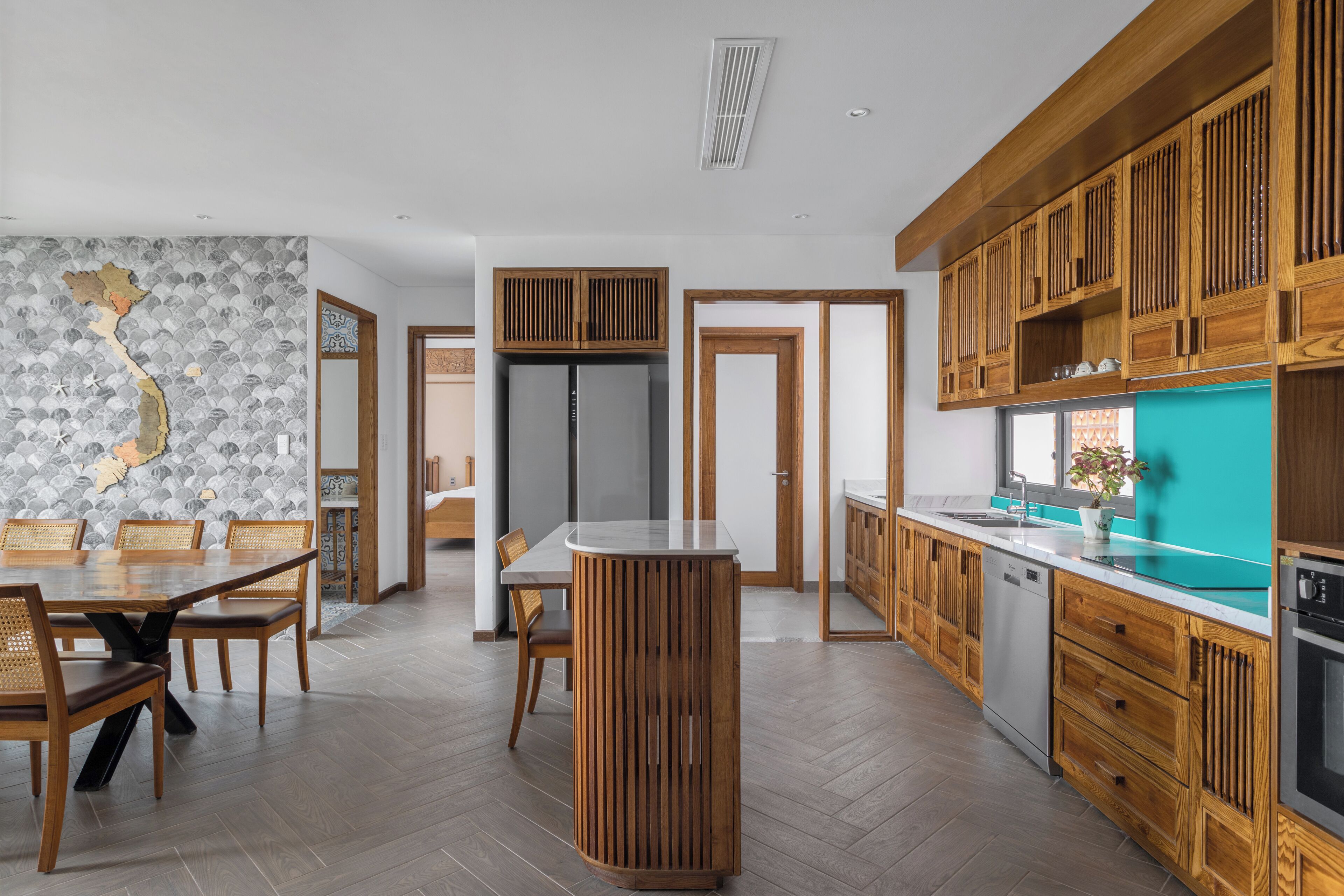 A modern kitchen with wooden cabinets, a central island, and a herringbone-patterned backsplash.