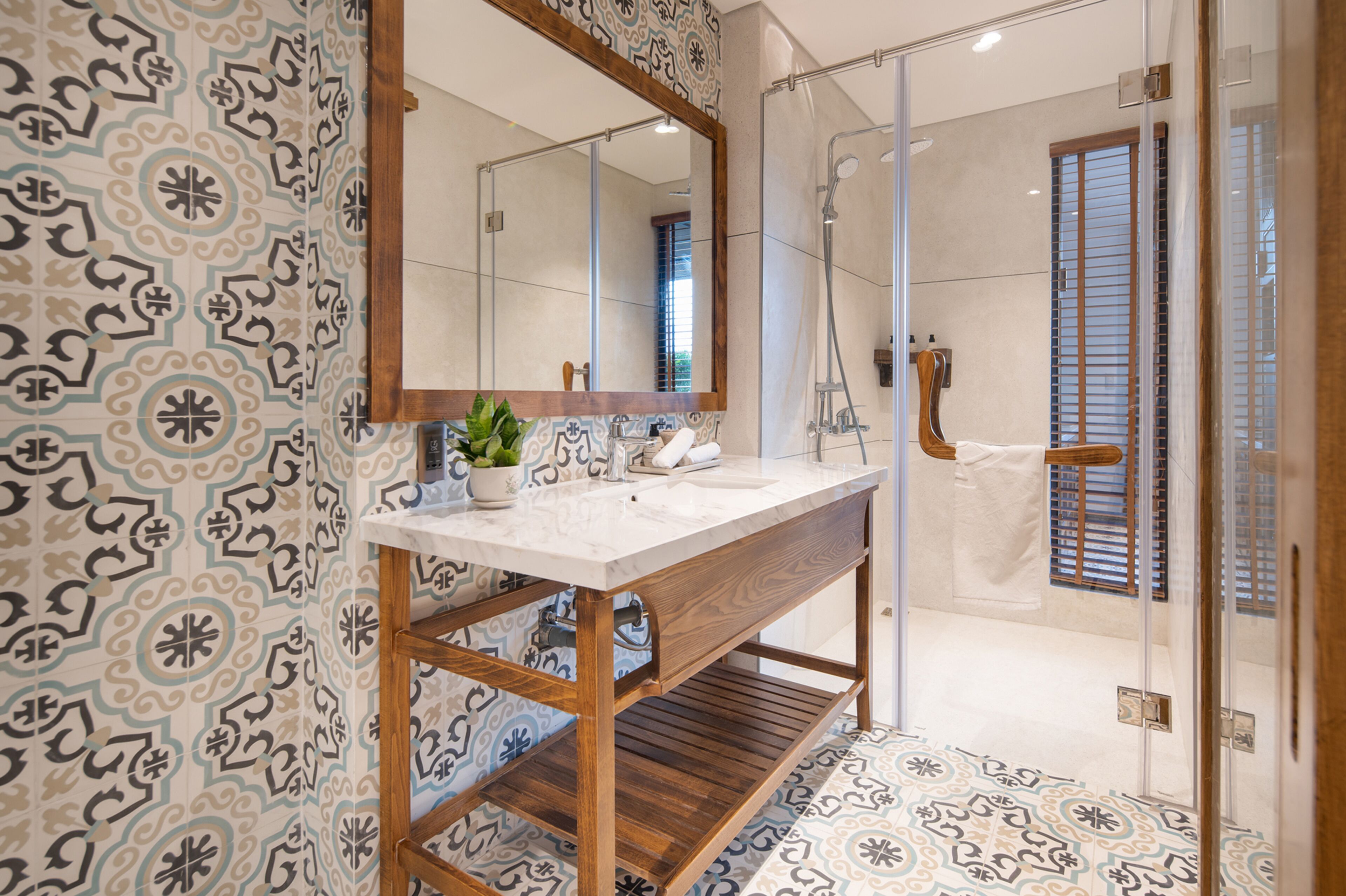 Une salle de bain avec un meuble-lavabo en bois, un grand miroir et des carreaux décorés.
