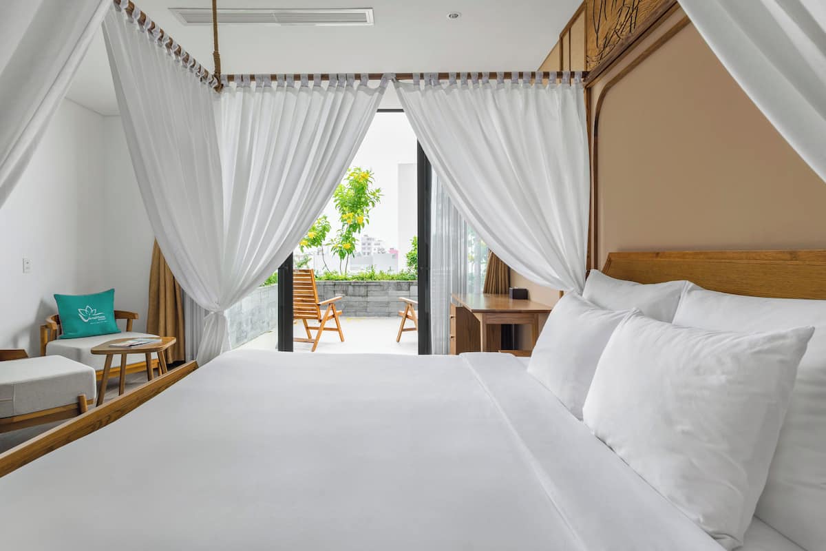 A bedroom with a large bed, a wooden headboard, and a view of the outdoors through a glass door.