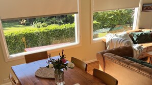 A wooden dining table with chairs, a vase with flowers, and a notebook. - Prime Spot! 5mins to “Grand Cliff Top Walk” & “3 Sisters” (Katoomba)