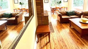 A spacious living room with a large mirror, wooden flooring, and multiple seating areas including sofas and a dining table. - Prime Spot! 5mins to “Grand Cliff Top Walk” & “3 Sisters” (Katoomba)
