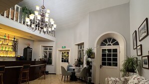 Un hall con zona de bar, asientos y una lámpara de araña.