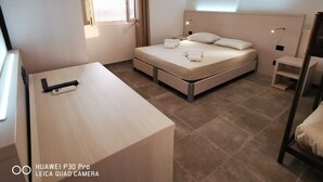 Habitación de hotel con cama, mesita de noche y escritorio con una cámara.