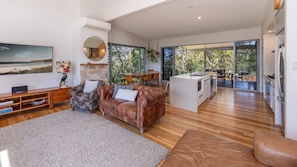 A spacious living area with a leather sofa, a flat-screen TV, and a stone accent wall.
