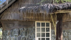 Un edificio rústico de piedra con techo de paja y puerta de madera.