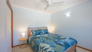 Ein Schlafzimmer mit einem Bett, einem Deckenventilator und zwei Nachttischlampen.