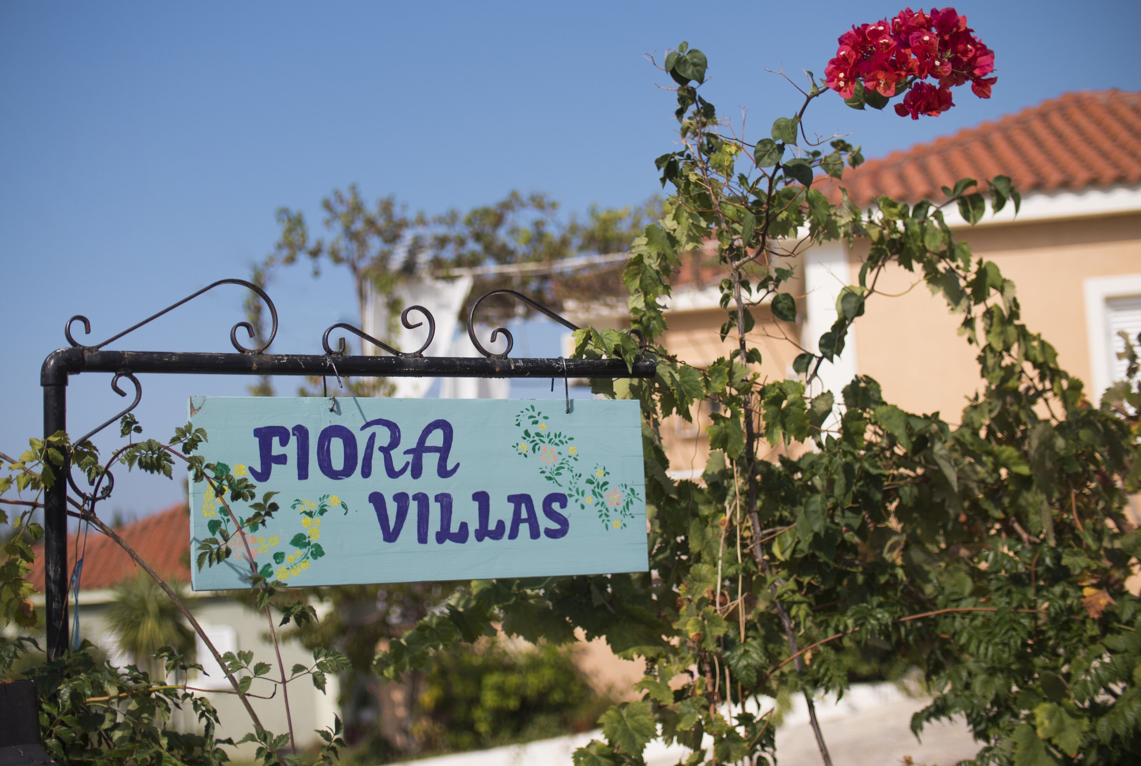 Ein Schild mit der Aufschrift 'Fiora Villas', im Hintergrund ist ein Haus gut sichtbar.