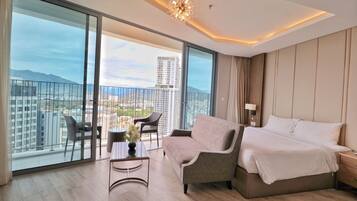 Habitación de hotel moderna con balcón, sofá, cama y una mesa con un florero.