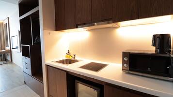 Una cocina moderna con armarios de madera, microondas integrado y un lavamanos de acero inoxidable.
