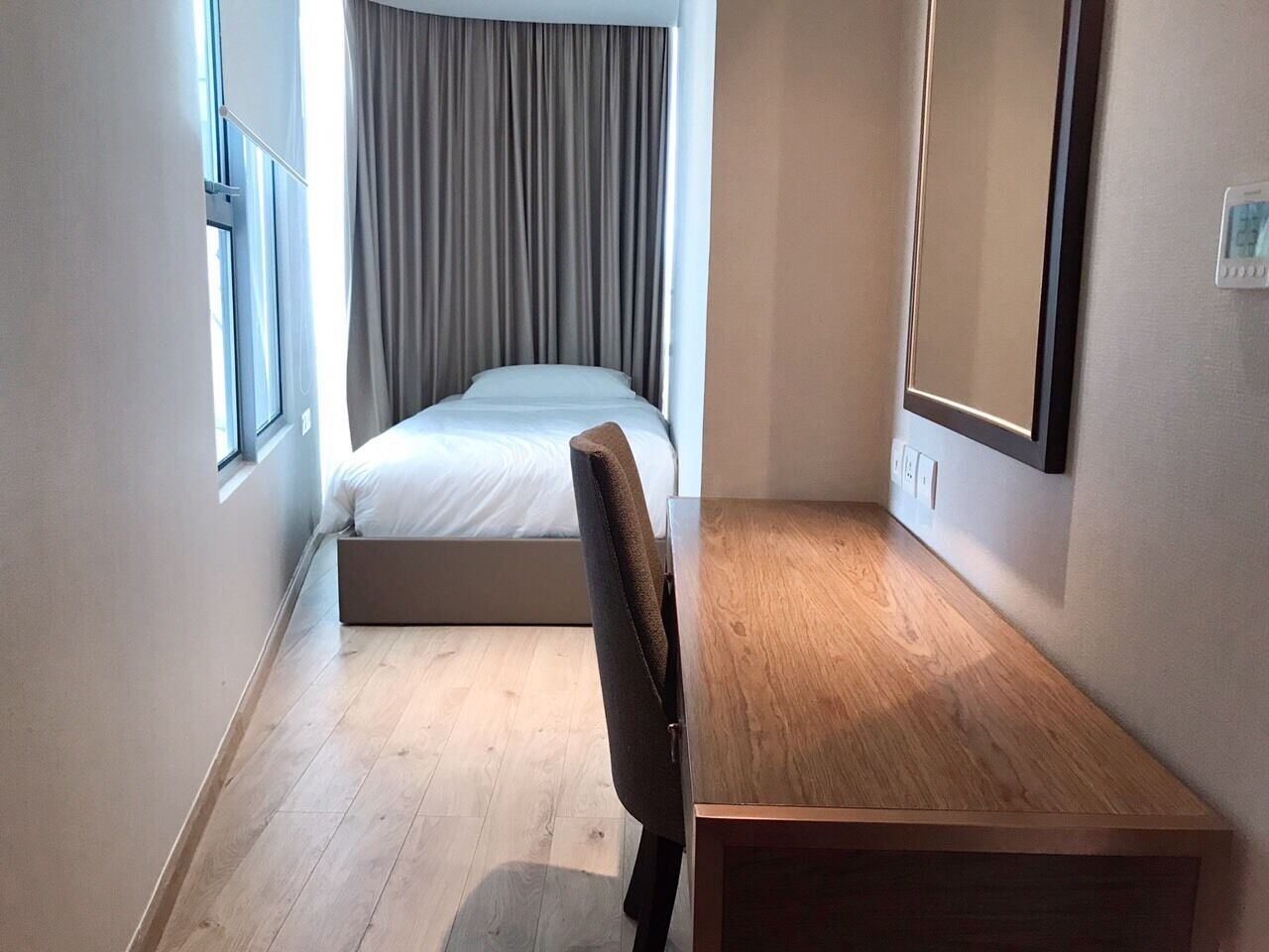 Une petite chambre moderne, équipée d’un lit, d’un bureau et d’une chaise.