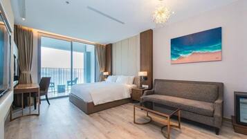 A modern hotel room with a large bed, a sofa, a desk, and a balcony with a view.