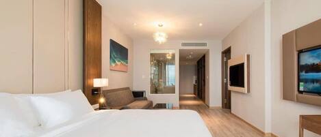 A hotel room with a large bed, a desk, a chair, a TV, and a painting on the wall.
