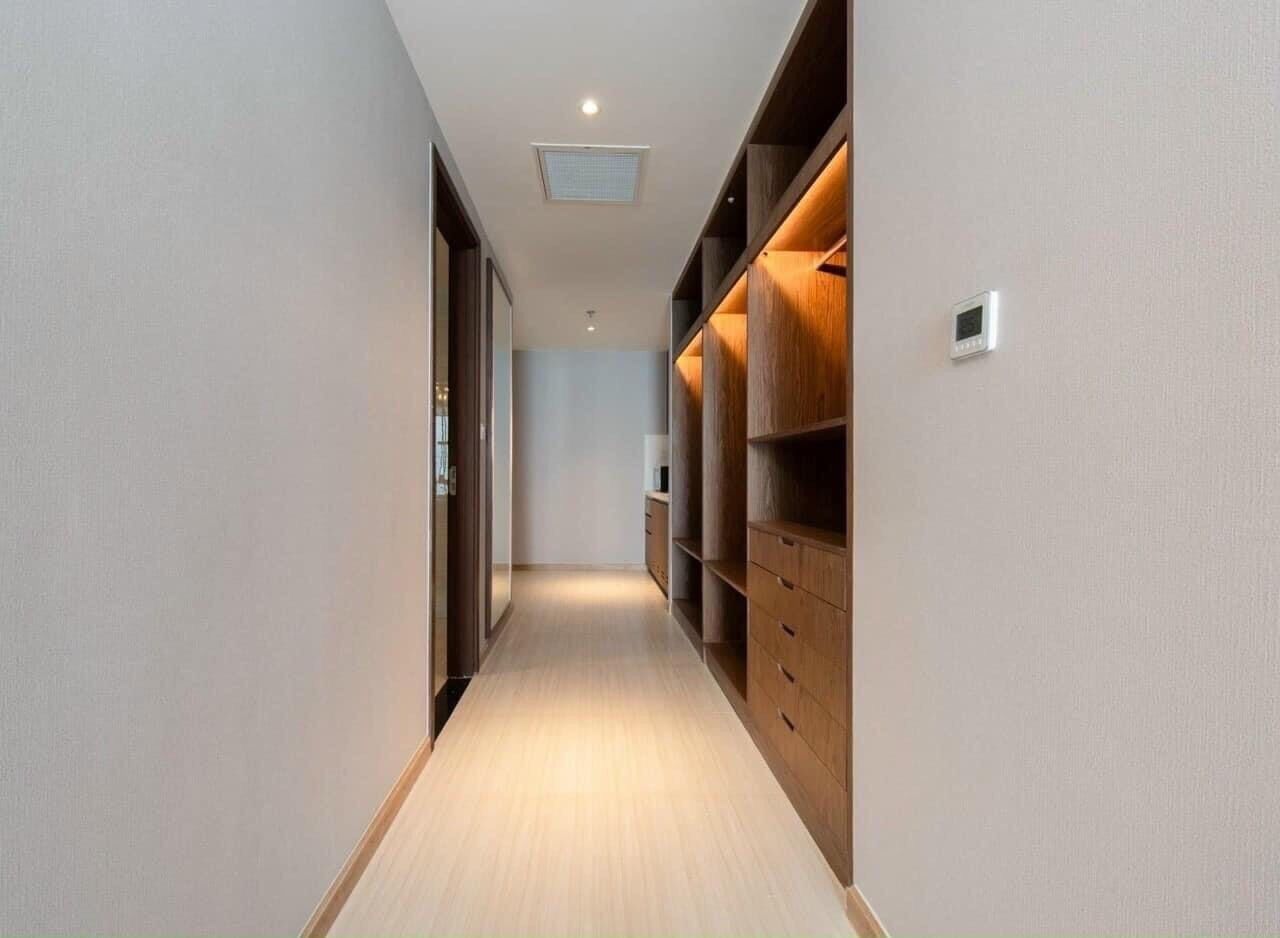 A narrow hallway with wooden shelving units on one side and a door on the other.