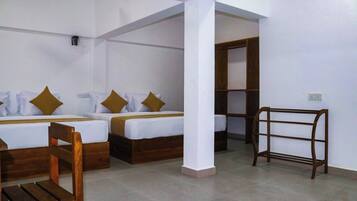 A hotel room with two beds, a wooden chair, a small table, and a bookshelf.